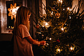 Mädchen beim Schmücken des Weihnachtsbaums zu Hause
