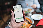 Person hält Smartphone mit Restaurantbewertungs-App