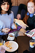 Young woman paying with card in cafe