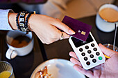 Young woman paying with card in cafe