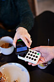 Young woman paying with phone in cafe