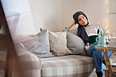 Lesende Frau auf Sofa im Wohnzimmer