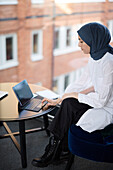 Geschäftsfrau im Hijab arbeitet mit digitalem Tablet im Büro