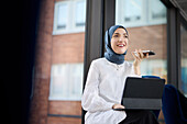Geschäftsfrau in Hijab benutzt Telefon und digitales Tablet im Büro