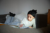 Girl doing homework with laptop in her bedroom