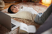 Girl with laptop lying on floor in her bedroom