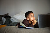 Boy doing homework with laptop in his bedroom