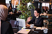 Lächelnde Geschäftsfrau mit Laptop in einem Café