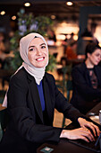 Geschäftsfrau schaut im Café in die Kamera