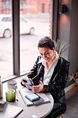 Reife Frau mit Handy in einem Café