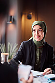 Frau mit Kopftuch sitzt in einem Café