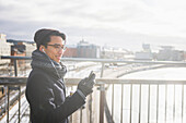 Schöner Mann mit Smartphone auf Fußgängerbrücke