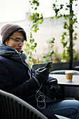 Mann mit Mobiltelefon in einem Straßencafé