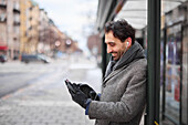 Elegant man with smartphone waiting on bus stop