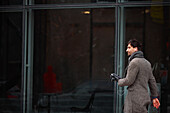 Eleganter Mann mit Smartphone, der auf der Straße geht