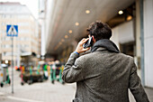Rear view of man talking on phone in street
