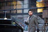 Businessman using phone outdoors in city