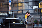 Businessman using phone outdoors in city