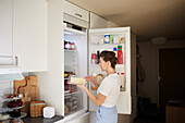 Frau steht vor offenem Kühlschrank