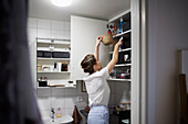 Woman putting basket in cupboard