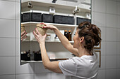 Woman putting basket in cupboard