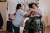 Mother with daughter on wheelchair in living room