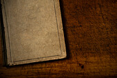 Altes Buch mit unbedrucktem Einband auf einer alten hölzernen Schreibtischplatte