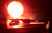 Close-up of a record player needle on record in orange light