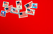 Retro postage stamps and American flag against red background