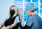 Frau mit Gesichtsmaske erhält Covid-19-Impfung