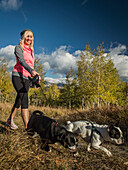 Smiling woman with two dogs walking in grassy field