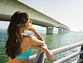 Woman relaxing on bridge on sunny day