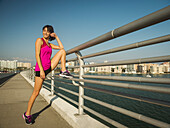United States, Florida, Sarasota, Smiling woman stretching on bridge on sunny day