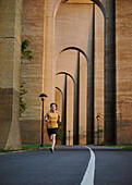 Mann joggt unter einer Brücke