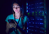 Female technician using smart phone in server room