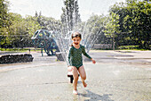 USA, New York, New York City, Mädchen spielt auf einem Spielplatz neben einem Wassersprinkler