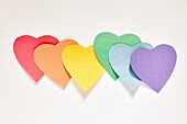 Studioaufnahme einer Reihe von regenbogenfarbenen Papierherzen