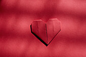 Rotes Origami-Herz auf rotem Hintergrund 