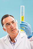 Scientist looking at yellow liquid in measuring beaker