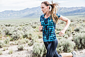 Vereinigte Staaten, Utah, Cedar Fort, Frau joggt in Wüstenlandschaft