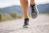 Close-up of feet of woman jogging in desert landscape