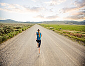 United States, Utah, Cedar Fort, Rear view of woman jogging on road in desert landscape