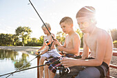 Three shirtless boys (8-9) fishing on lake