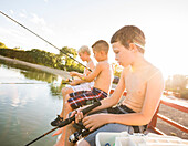 Three shirtless boys (8-9) fishing on lake