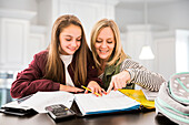 Mother helping daughter (12-13) doing homework at desk