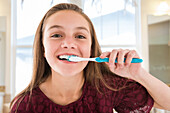 Portrait of smiling girl (12-13) brushing teeth