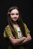 Studio portrait of smiling girl (10-11) in green dress with flower in hair