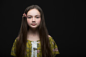 Studio-Porträt von Mädchen (10-11) in grünem Kleid mit Blume im Haar