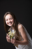 Studio portrait of smiling girl (10-11) holding bunch of wildflowers