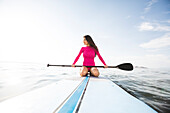 Woman kneeling on paddleboard 